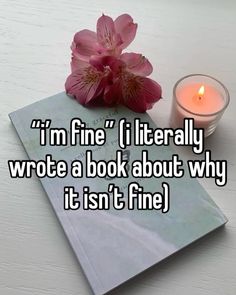 a pink flower sitting on top of a book next to a lit candle with the words i'm fine if literally wrote a book about why it isn't fine