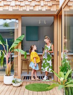 two women and a child standing in front of a kitchen with wooden siding on the walls