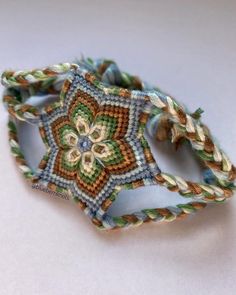 a close up of a bracelet on a white surface with an intricate flower design in the center