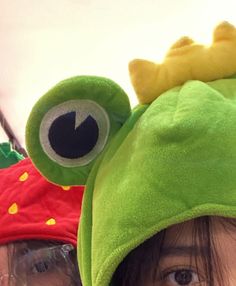 two young children wearing hats with eyes and one has a green frog on it's head