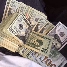 a pile of twenty dollar bills sitting on top of someones jeans in their lap