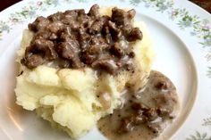 a white plate topped with mashed potatoes covered in gravy