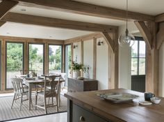 an open kitchen and dining room area with wooden beams on the ceiling, glass doors leading to outside