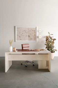 an office desk with a chair and potted plant