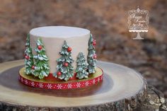 a decorated christmas cake sitting on top of a wooden table next to a tree stump