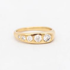 a yellow gold ring with five diamonds on the side, set against a white background