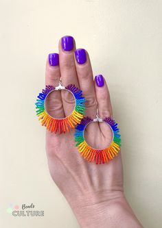 a woman's hand holding two colorful earrings