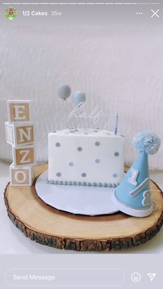 a white cake with blue decorations sits on top of a wooden slice that says happy birthday