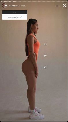 a woman in an orange swimsuit is standing and looking at the side of her body