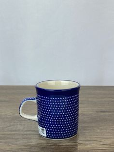 a blue and white coffee cup sitting on top of a wooden table