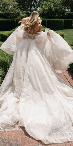 a woman in a white wedding dress walking down a path