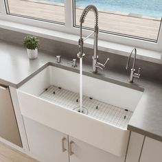 a white kitchen sink sitting under a window next to a potted plant on top of a counter