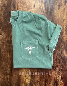 Medical Caduceus pocket t-shirt ➡️Image on left chest ➡️Screen printed design  ➡️Made with adult unisex Comfort Colors pocket t-shirts ➡️ Loose comfort fit. Er Shirts Ideas, Casual Cotton T-shirt For Nursing, Casual Relaxed Fit Nursing T-shirt, Cotton Nursing T-shirt Relaxed Fit, Cotton Relaxed Fit T-shirt For Nursing, Relaxed Fit Cotton T-shirt For Nursing, Relaxed Fit Cotton Nursing T-shirt, Doctor T Shirt, Nursing Things