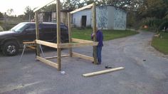 a man standing in front of a wooden structure on the side of a road next to a truck