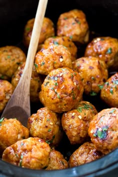 a wooden spoon in a slow cooker filled with meatballs