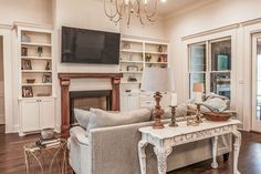 a living room filled with furniture and a flat screen tv mounted to a wall above a fireplace