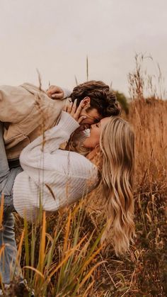 a man and woman are kissing in the middle of tall grass with their heads close to each other