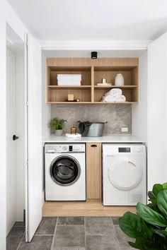 a washer and dryer in a small laundry room with open shelving on the wall