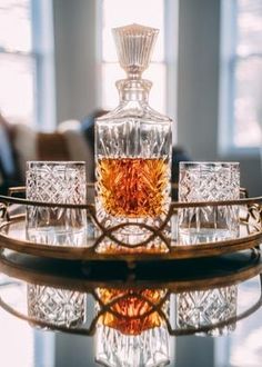 an empty glass bottle sitting on top of a table next to four glasses and a tray