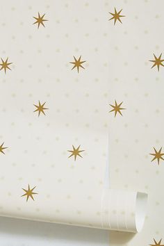 a white wall with gold stars on it next to a roll of tape and scissors