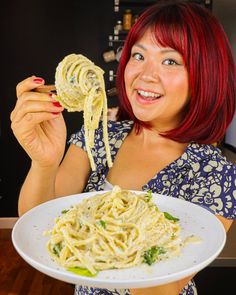 a woman with red hair holding a plate of spaghetti