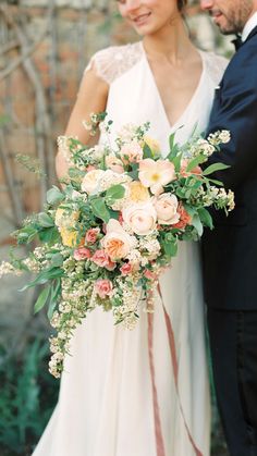 a man and woman standing next to each other holding flowers