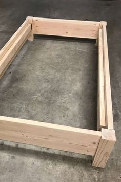 a wooden bed frame sitting on top of cement flooring in a room with concrete floors