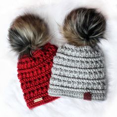 two crocheted hats with pom - poms are laying next to each other