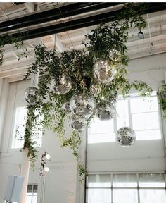 a room filled with lots of glass balls hanging from the ceiling and greenery on the ceiling