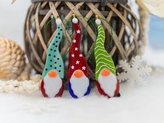 three christmas ornaments sitting on top of snow covered ground