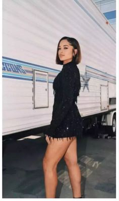 a woman standing in front of a trailer with her legs crossed and wearing short shorts