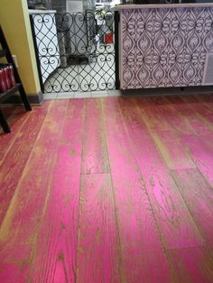 a wooden floor with pink paint on it in front of a metal fence and window