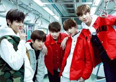 group of young men standing next to each other on a subway train, posing for the camera