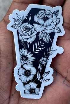 a hand holding a black and white sticker with flowers in the vase on it