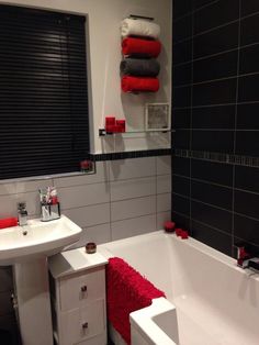 a white bath tub sitting next to a sink under a window with red towels on it