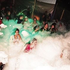 many people are playing in the foamy water at a party or socializing with each other