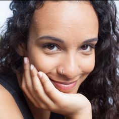 a close up of a person smiling with her hand on her chin and hands under her chin