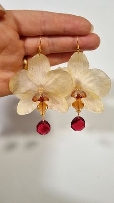 Natural flower earrings , real dry Orchid cover with resin . All earrings are made from real Orchid hand made carefully selected dry and cover with shiny and transparent resin. Unique pieces ,each flower is different, a unique, special pair.  option 1 -large cream orchid with red crystal option 2 -medium purple  option 3-medium transparent whithe with crystal option 4-large dark red-violet golden petal Contact me if need additional information. Check out my other listings there is more much more Orchid Clothes, Resin Flower Earrings, Orchid Accessories, Flower Earrings Diy, Real Flower Earrings, Orchid Jewelry, Yellow Orchid, Bijoux Art Nouveau