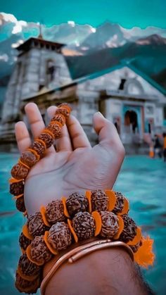 a person holding their hand up in front of a building with mountains in the background