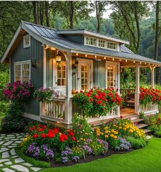 a small house with lots of flowers in the front and side windows on the porch