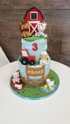 a three tiered cake with farm animals on the top and number 3 on the bottom