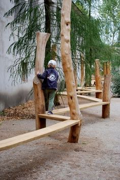 a person standing on a wooden bench made out of tree trunks in the middle of a park