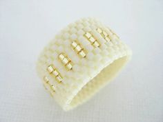 a close up of a ring made out of white material with gold rivets