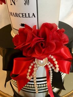 a red rose is on top of a black and white hat with pearls, beads and ribbon