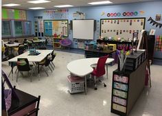 a classroom with tables, chairs and chalkboards on the wall in front of them