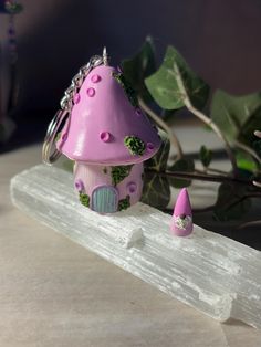 a small pink mushroom shaped house sitting on top of a piece of wood next to a plant