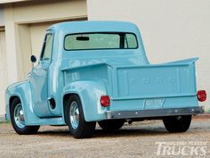 an old blue pick up truck parked in front of a building