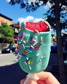 a hand holding up an ice cream sundae with sprinkles on it