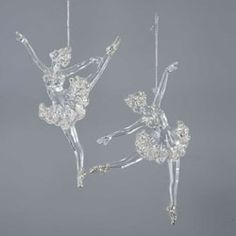 two crystal ballerinas hanging from chains on a gray background, one in the air