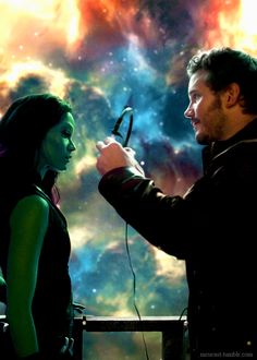 a man and woman standing next to each other in front of a colorful background with stars